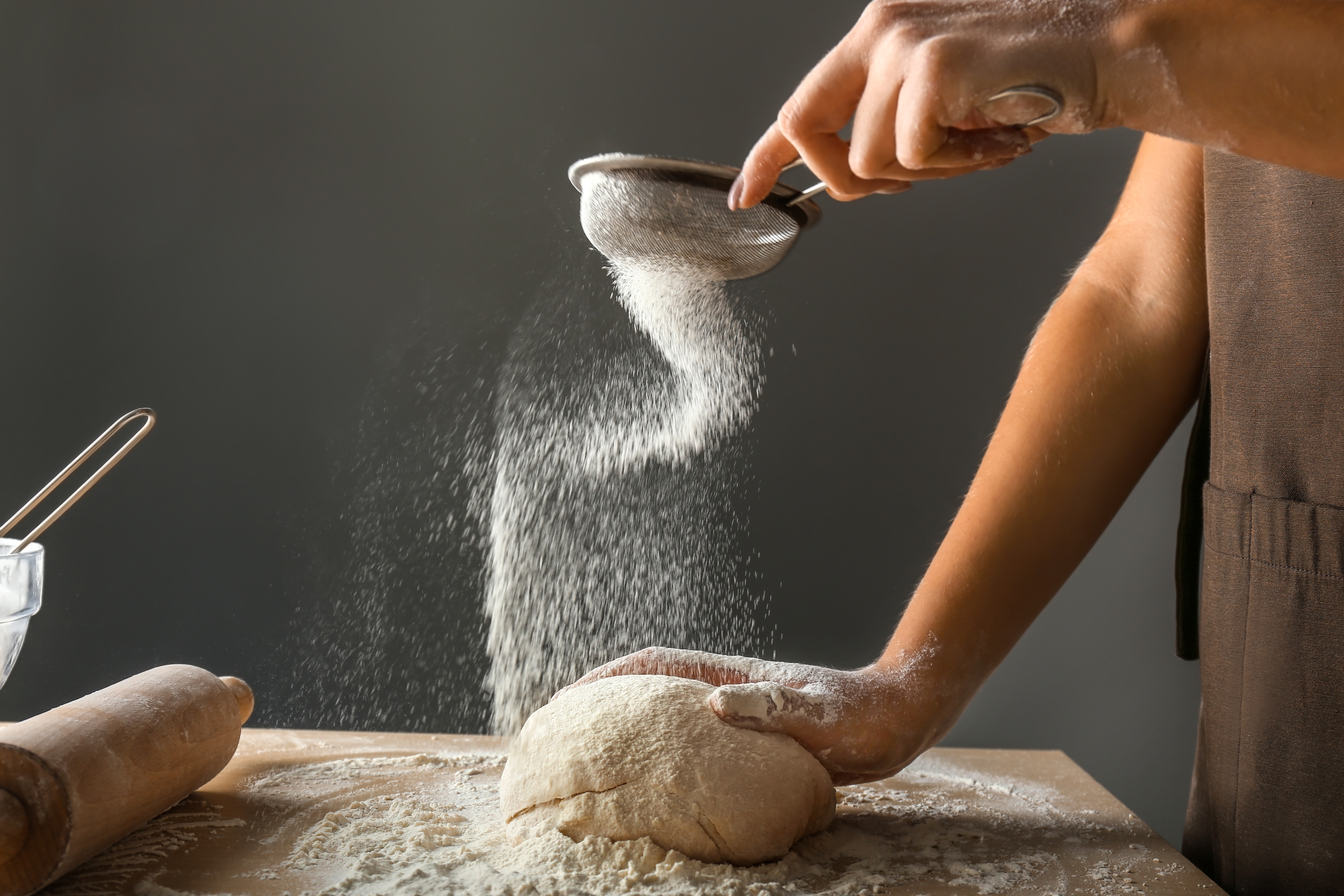 Person sifting flour while making bread